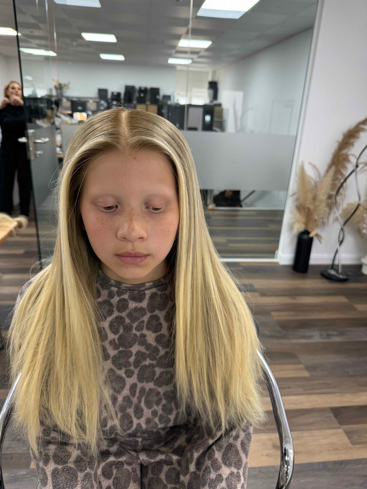 Child wearing a long blonde straight human hair wig, styled naturally,
against a white background – Nuola Wigs.