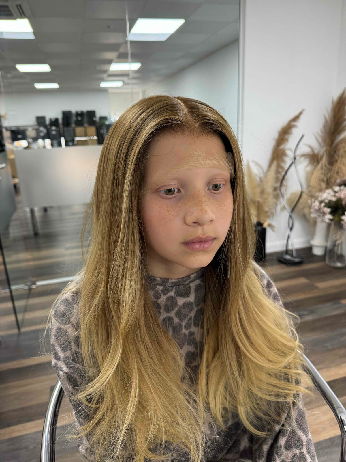 Child wearing a long blonde straight human hair wig, styled naturally,
against a white background – Nuola Wigs.