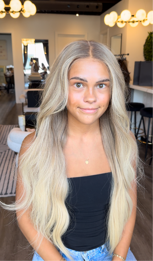 Model wearing blonde balayage 26-inch HD lace human hair wig in body wave
texture – Nuola Wigs.