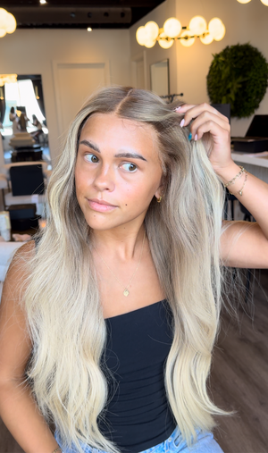 Model wearing blonde balayage 26-inch HD lace human hair wig in body wave
texture – Nuola Wigs.