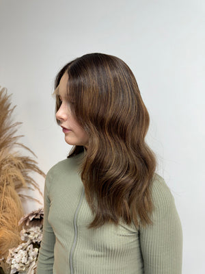 Child wearing a long brown wavy human hair wig, styled naturally,
against a white background – Nuola Wigs.