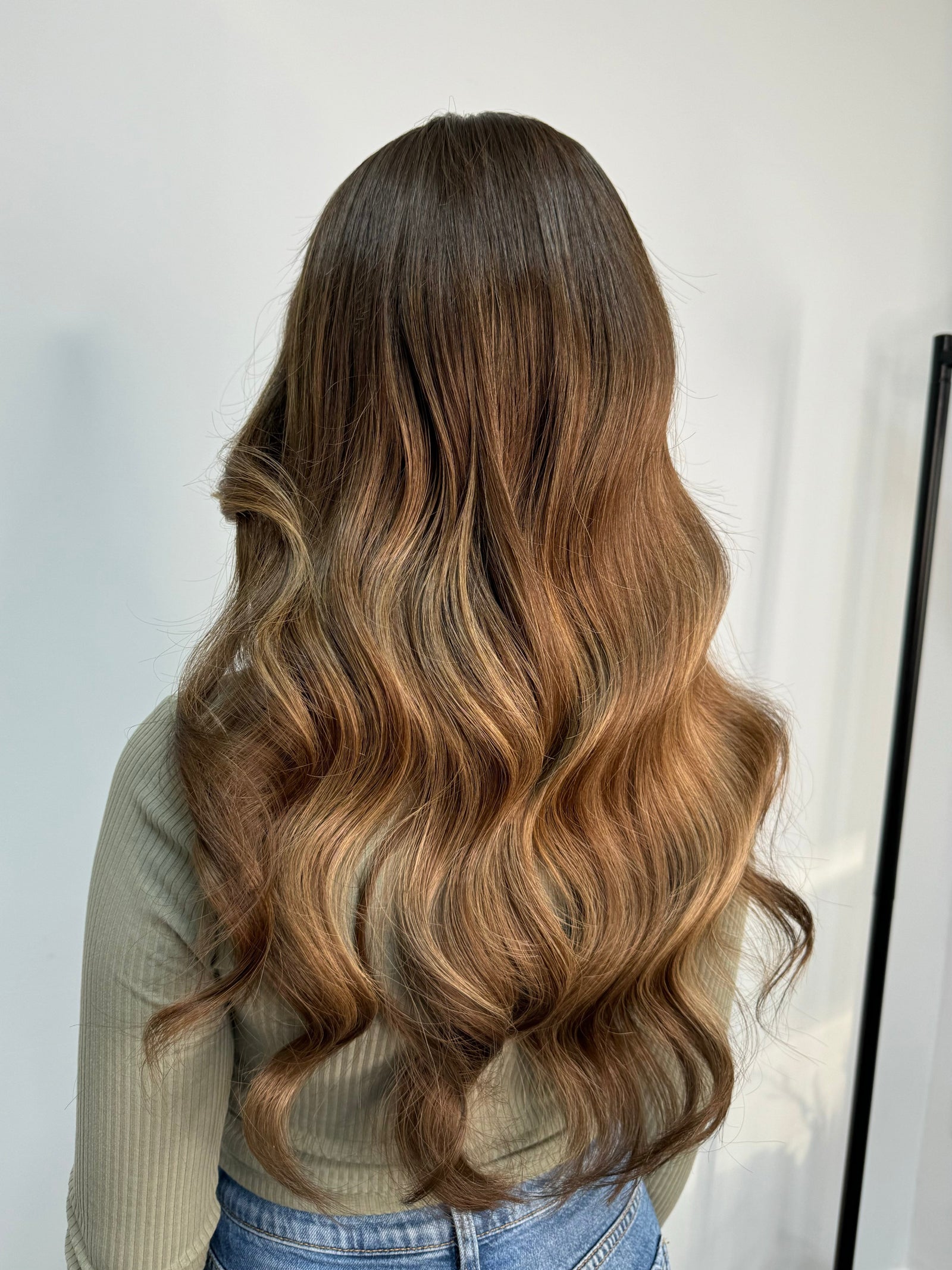 Child wearing a long brown wavy human hair wig, styled naturally,
against a white background – Nuola Wigs.